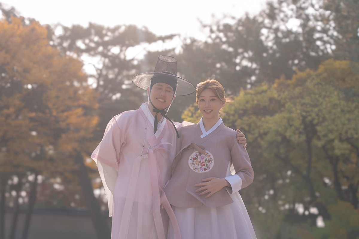 A hanbok couple photographed in soft autumn backlight
