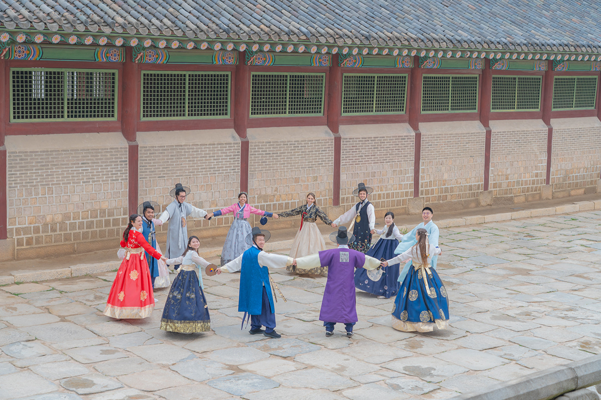 A large international group making a circle in hanbok at Gyeongbokgung