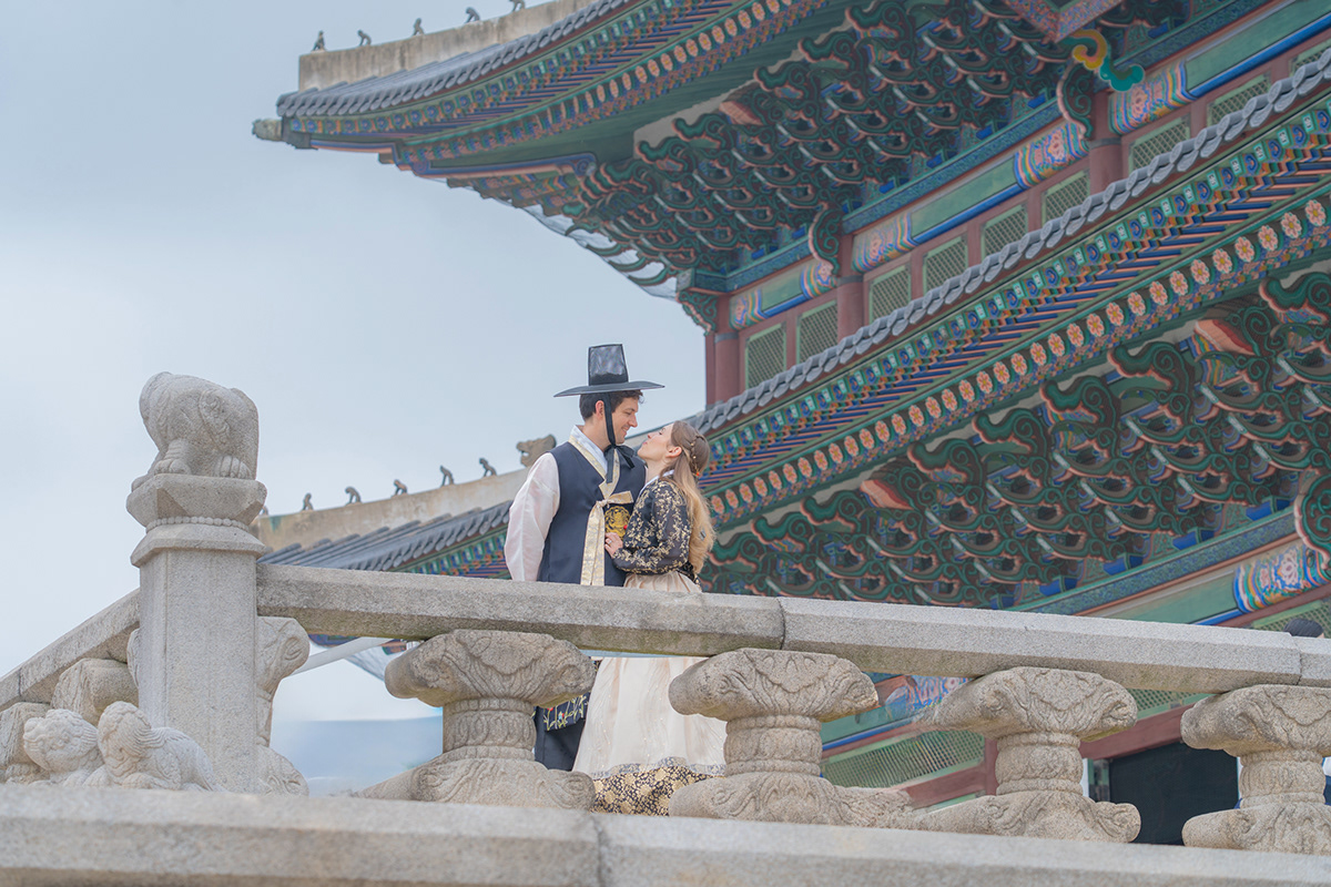 An international couple in hanbok beneath Gyeongbokgung architecture