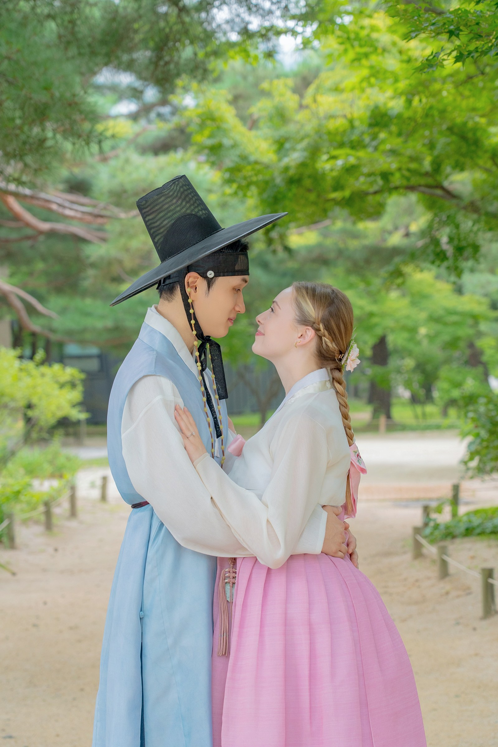 A couple in pale blue and pink hanbok sharing a quiet portrait at Gyeongbokgung