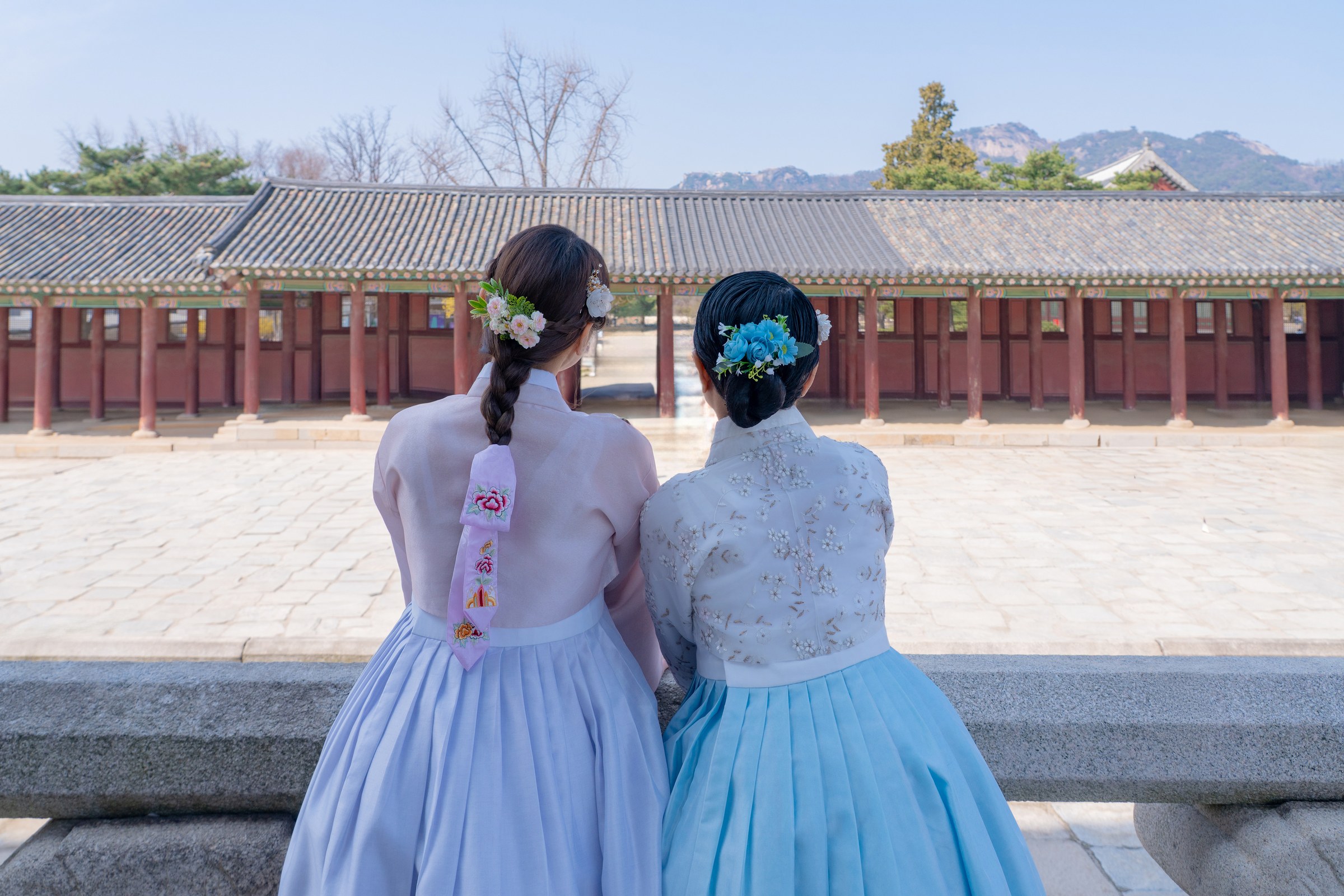 Two friends from the Philippines showing braided floral hair details in matching cool-tone hanbok