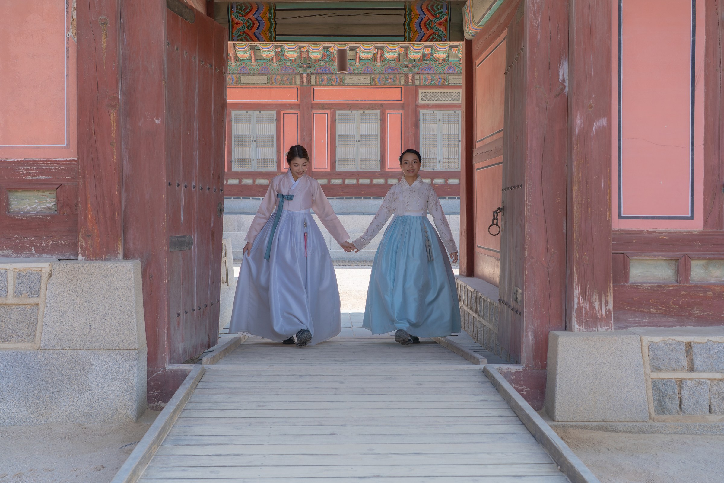 Two friends from the Philippines holding hands in a symmetrical Gyeongbokgung gateway